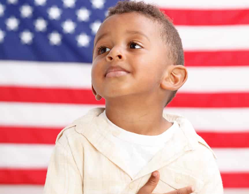 Boy in front of American flag with hand over heart Boy in front of American flag with hand over heart