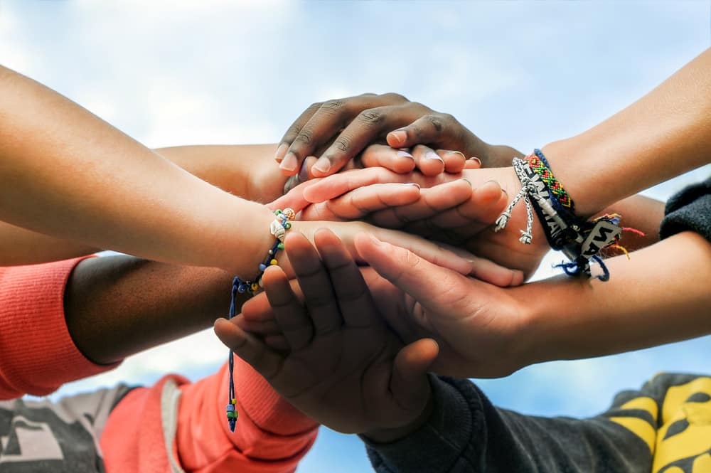 Multiracial,Teenagers,Joining,Hands,Together,In,Cooperation